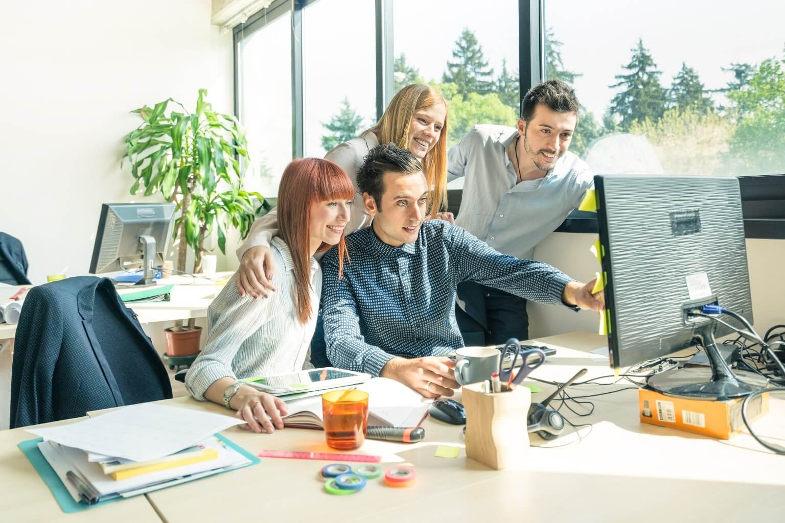 Travailler au Pays de Galles : jeunes souriants rassemblés autour d'un ordinateur au travail